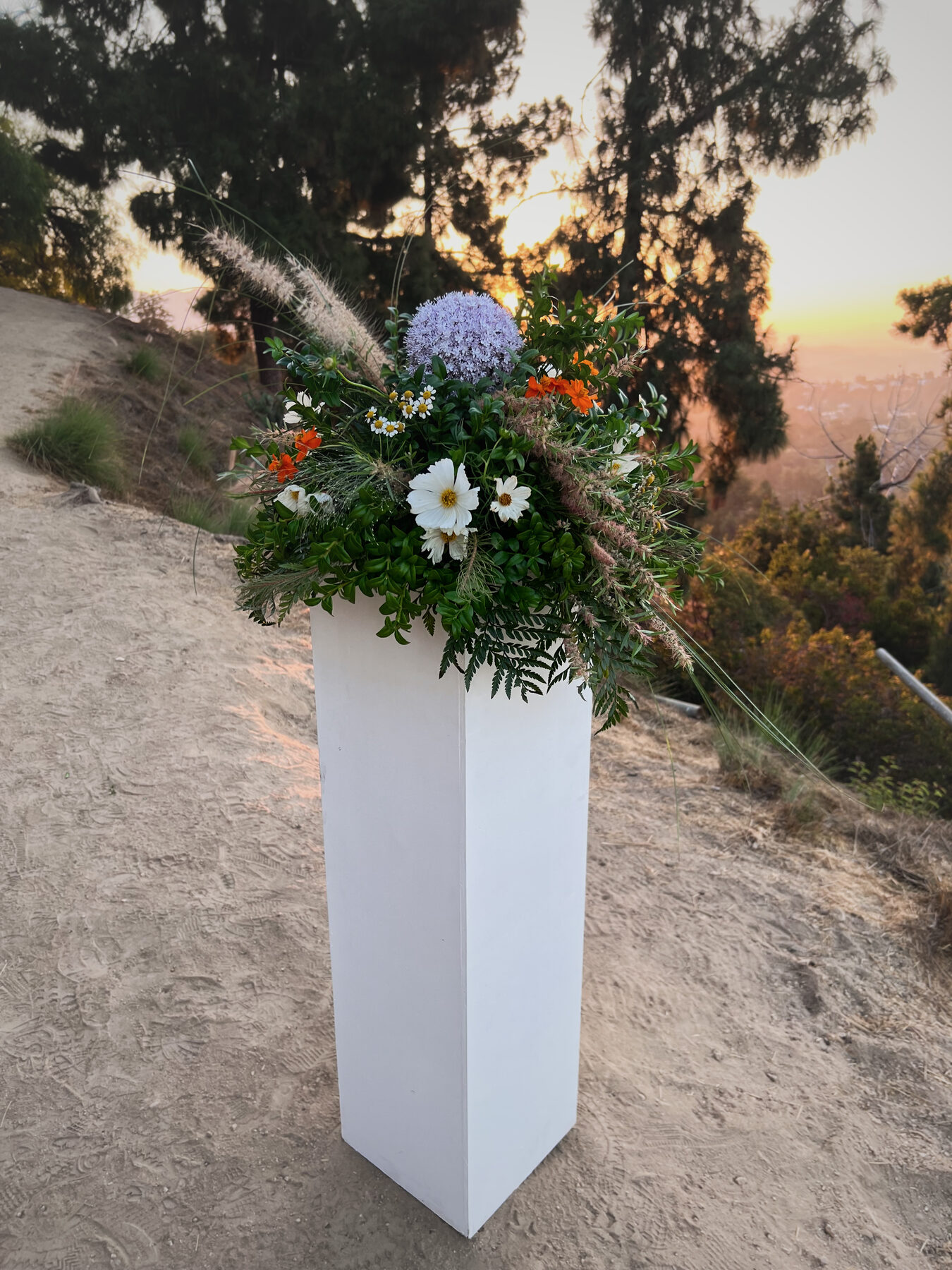 Wildflower and allium pillar arrangement on a hillside at sunset
